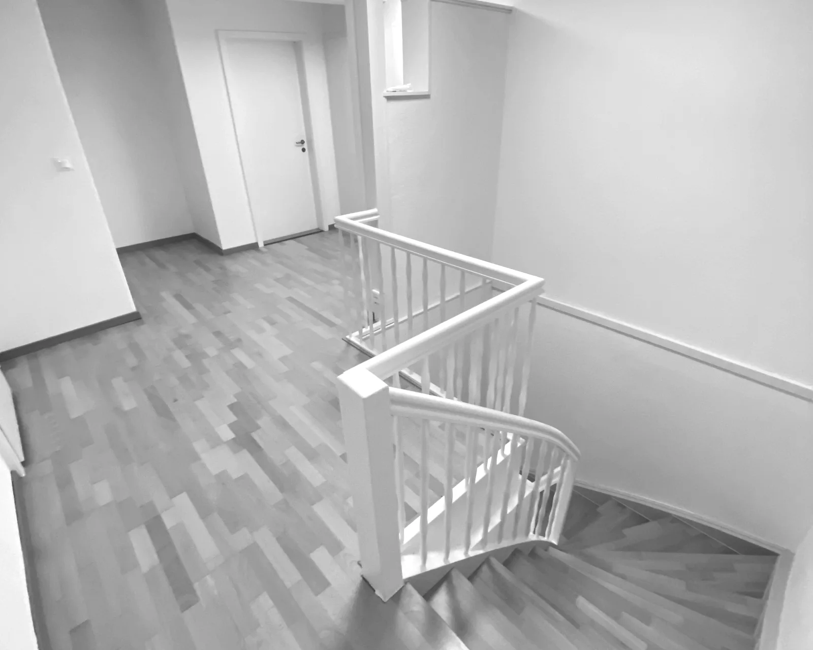 Saniertes Treppenhaus mit weiss lackiertem Geländer und durchgehendem Dielenboden