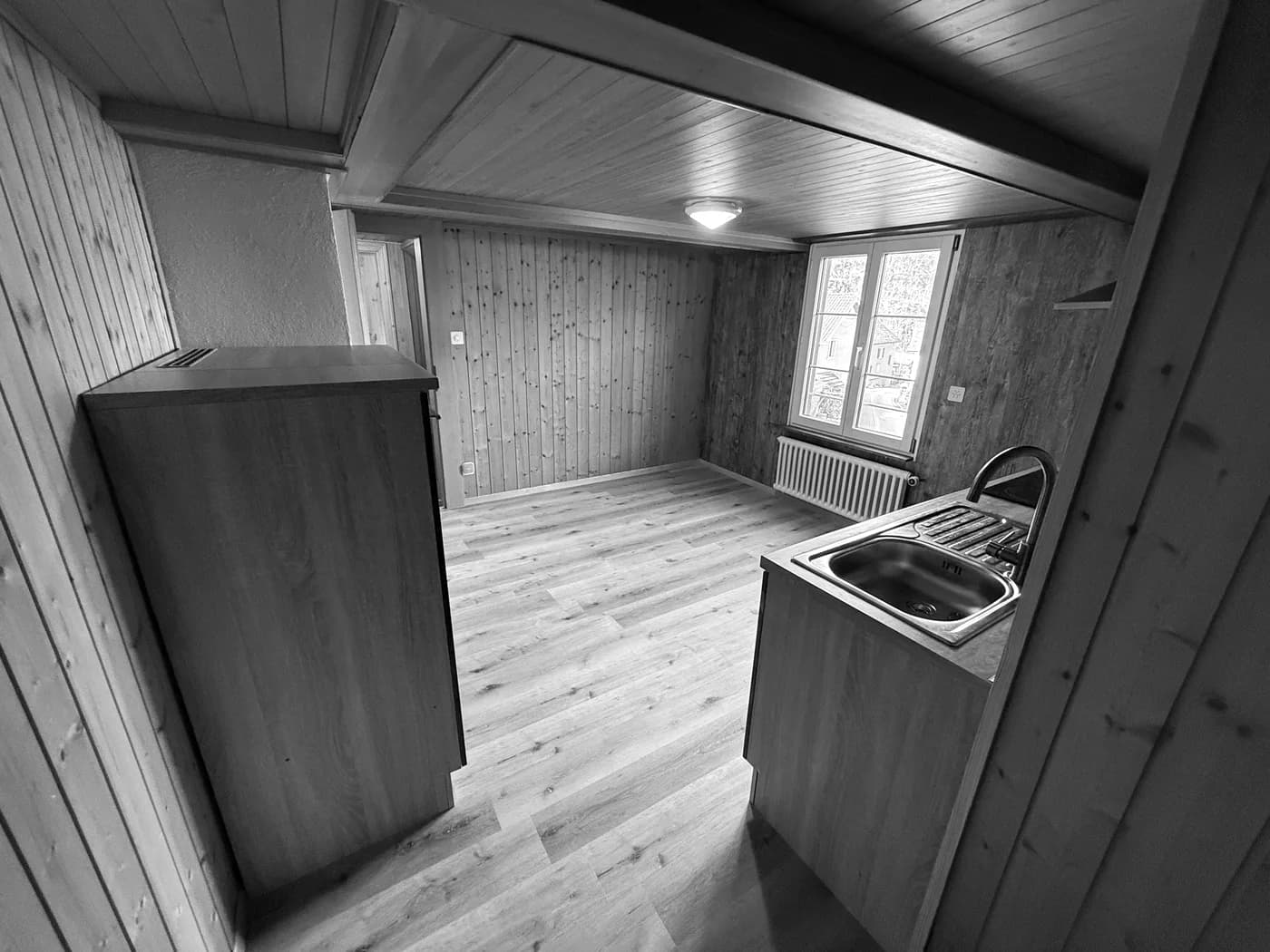 Ausgebauter Wohnraum mit Holzverkleidung, neuer Küchenzeile und neuem Bodenbelag